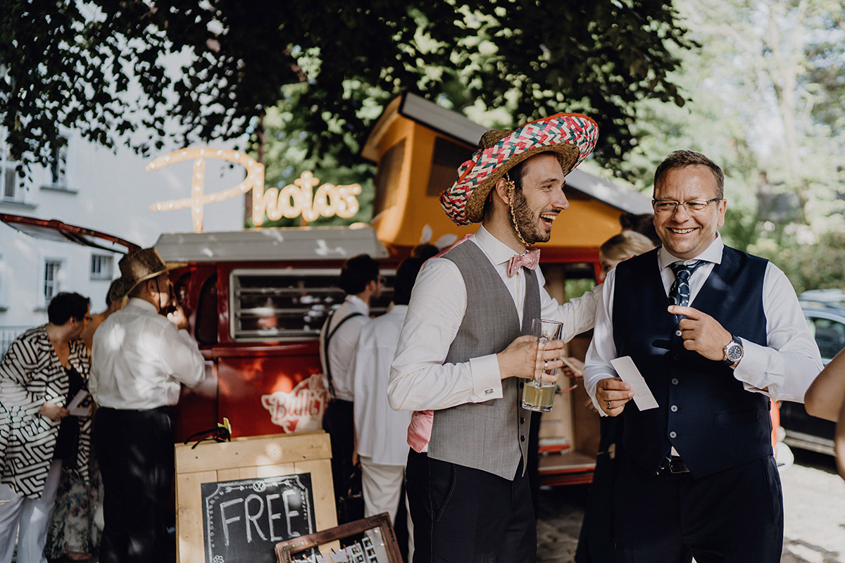 Gäste posieren vor lustigem Photobooth Hintergrund bei Boho Hochzeit