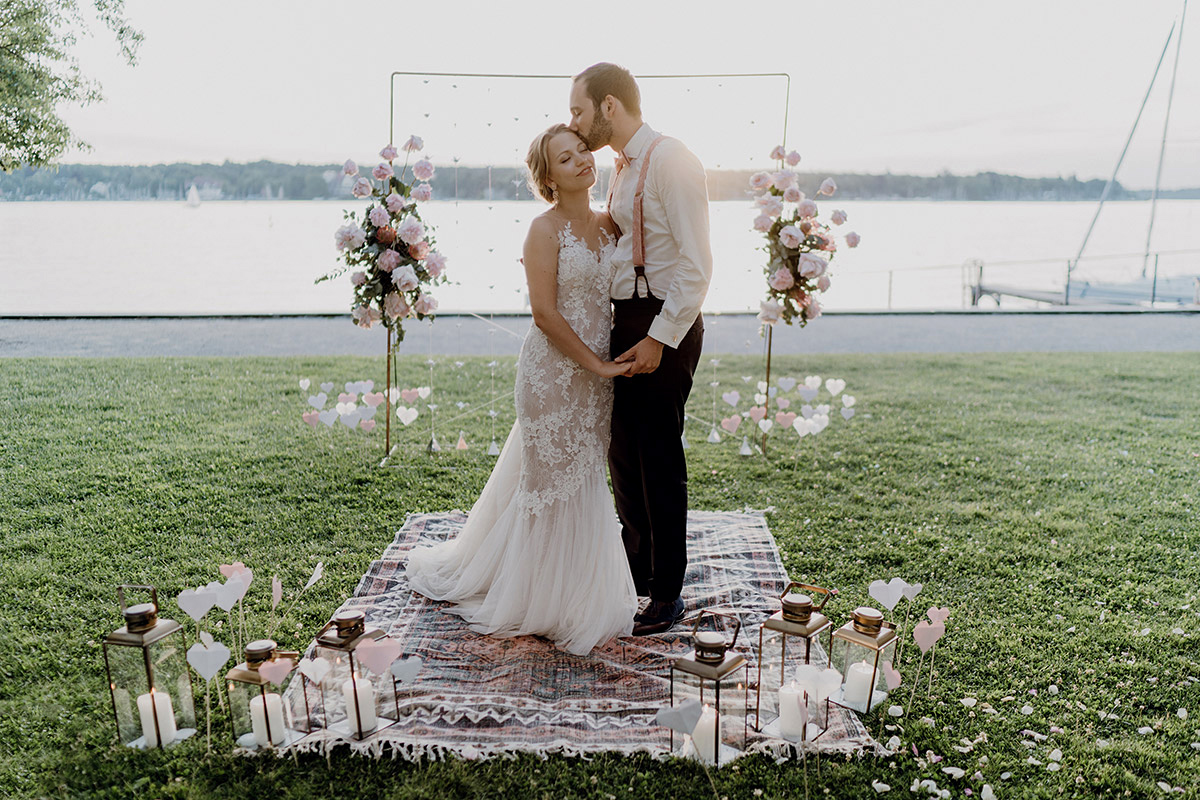 Boho Hochzeit am Wannsee: Brautpaar steht auf Teppich direkt am Wasser – Hochzeitsfotos Villa Blumenfisch Berlin