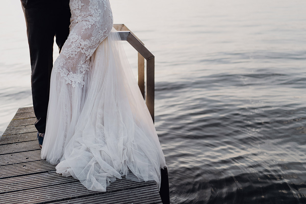 Detailaufnahme: Brautkleid Textur vor dem glitzernden Wasser des Sees
