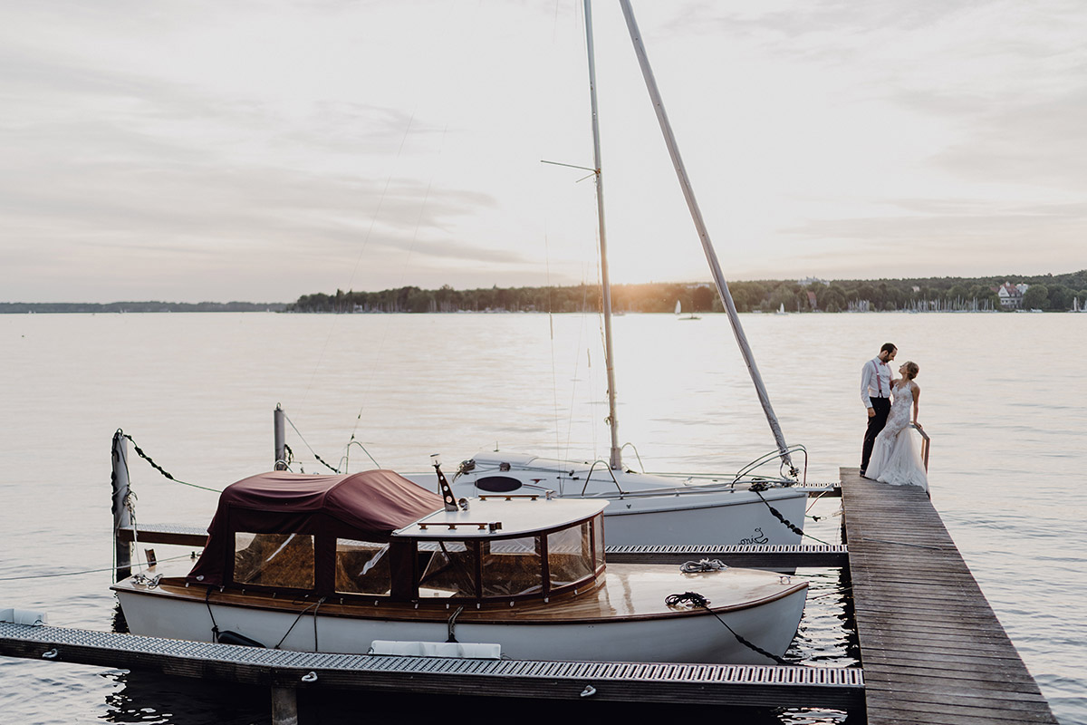 Brautpaar steht bei Villa Blumenfisch Hochzeit zum Sonnenuntergang auf Steg am Wannsee – Foto & Video Berlin
