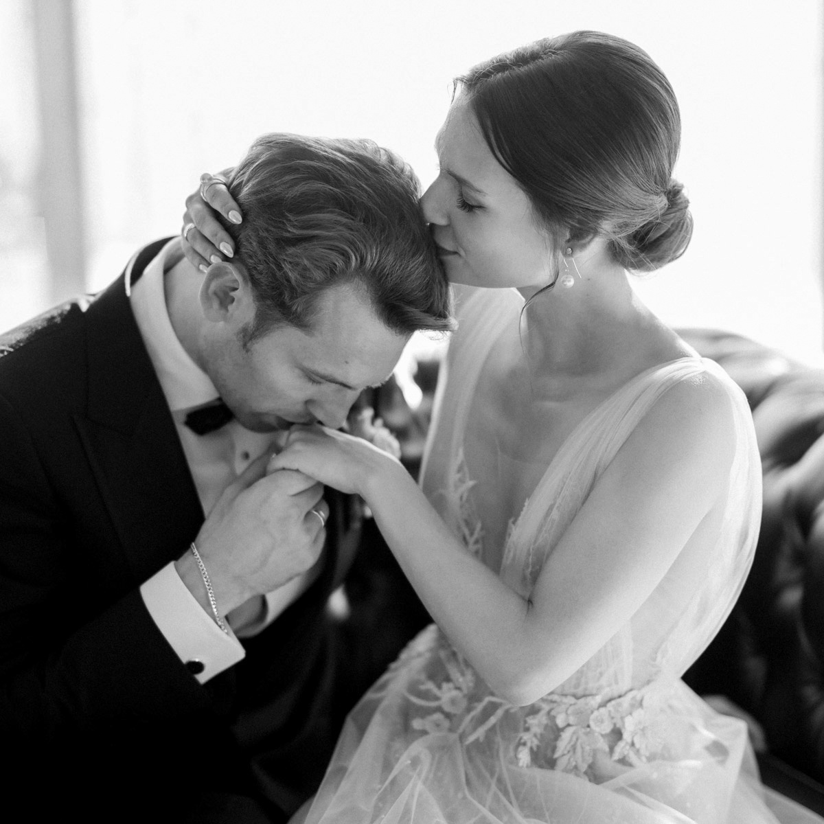 Romantisches Brautpaarfoto: Bräutigam küsst Hand und Braut küsst Kopf des Bräutigams