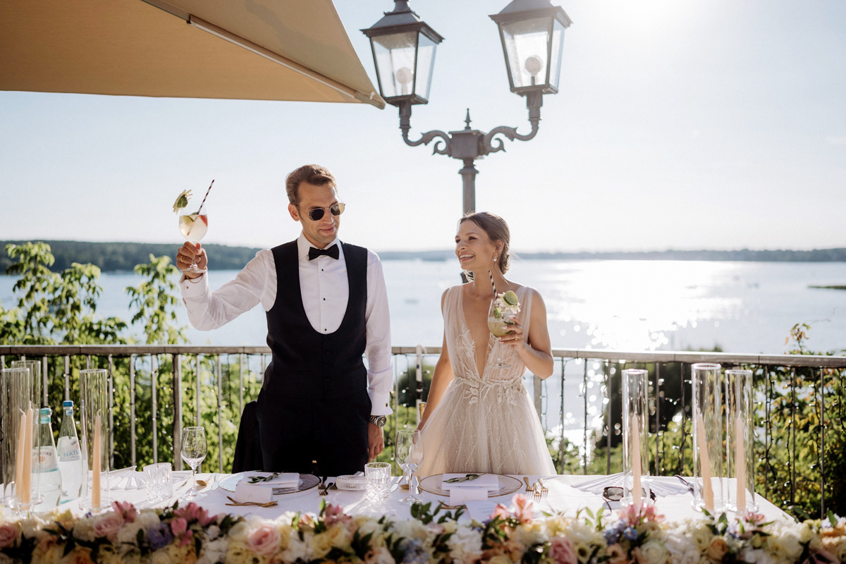 Brautpaar steht mit Getränken auf Terrasse und hält Willkommensrede