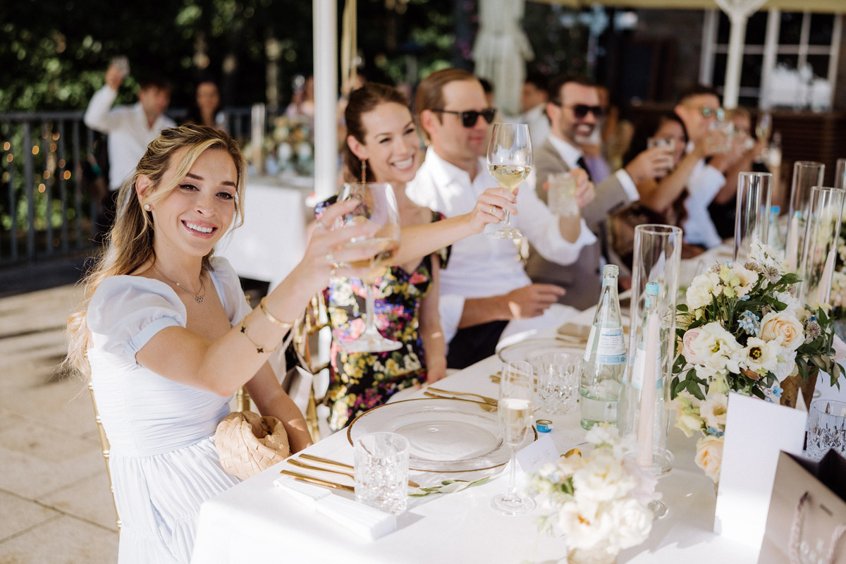Hochzeitsgäste am Tisch stoßen auf Brautpaar an