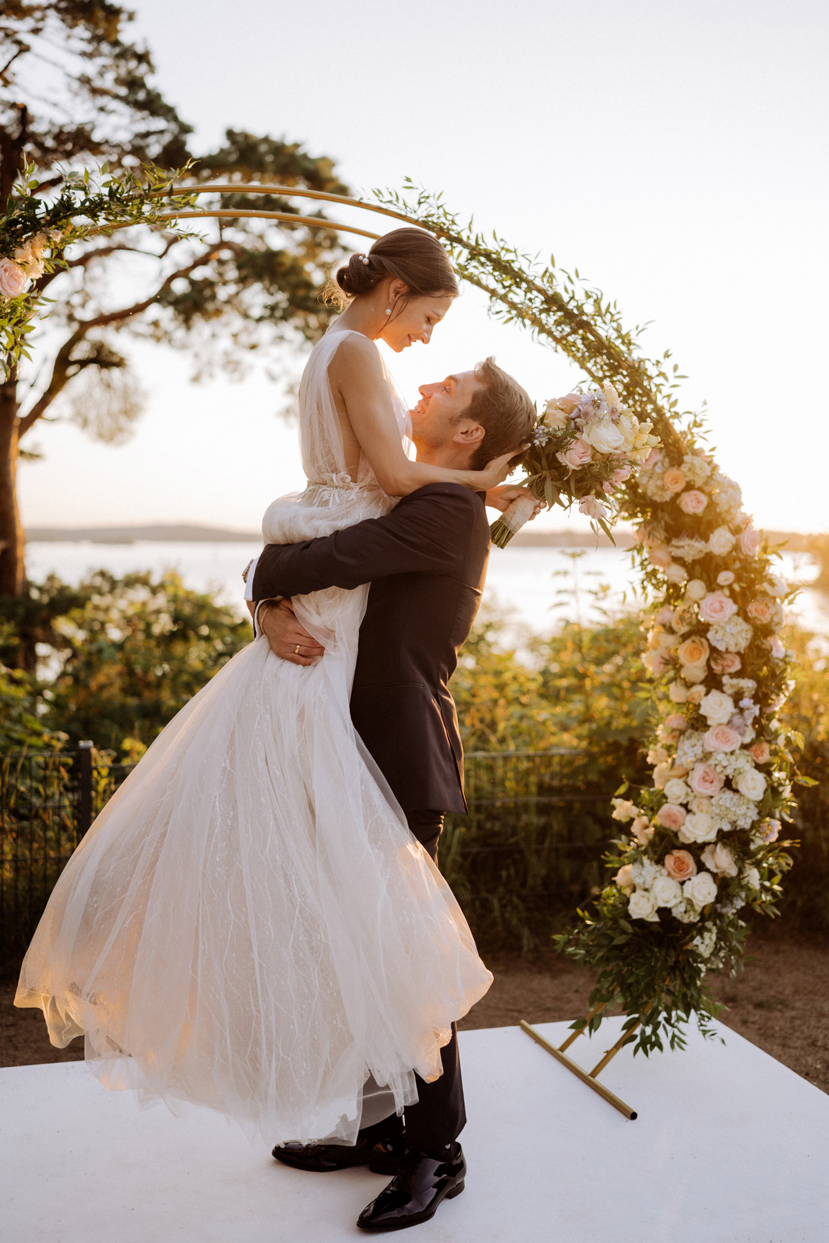 Fine Art Hochzeitsfoto am Berliner Wannsee: Das Brautpaar feiert im warmen Licht des Sonnenuntergangs an der Location am Wasser.