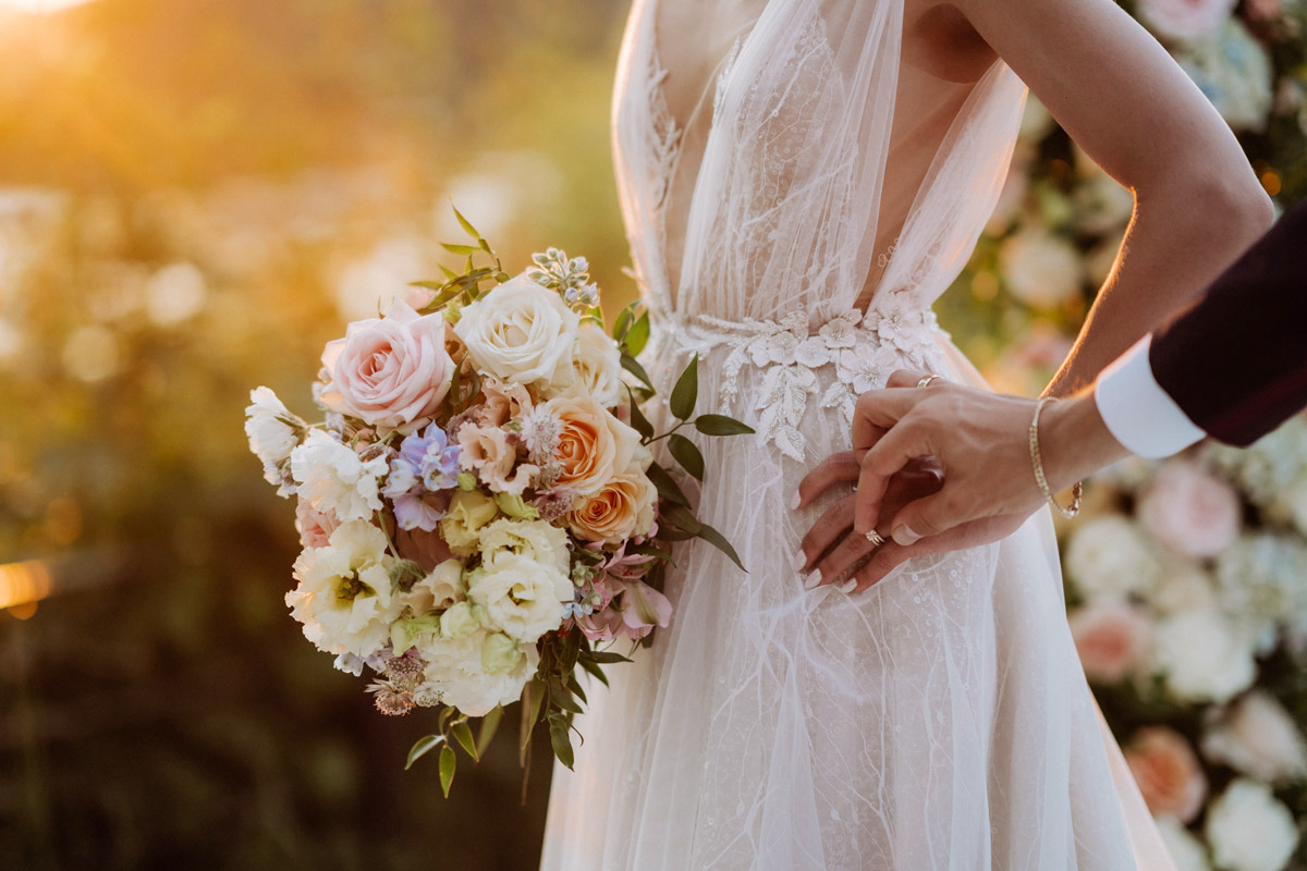 Detailaufnahme einer internationalen Hochzeit in den Wannseeterrassen Berlin: Braut im Spitzenkleid mit Brautstrauß im goldenen Abendlicht – English speaking wedding photographer captures romantic details