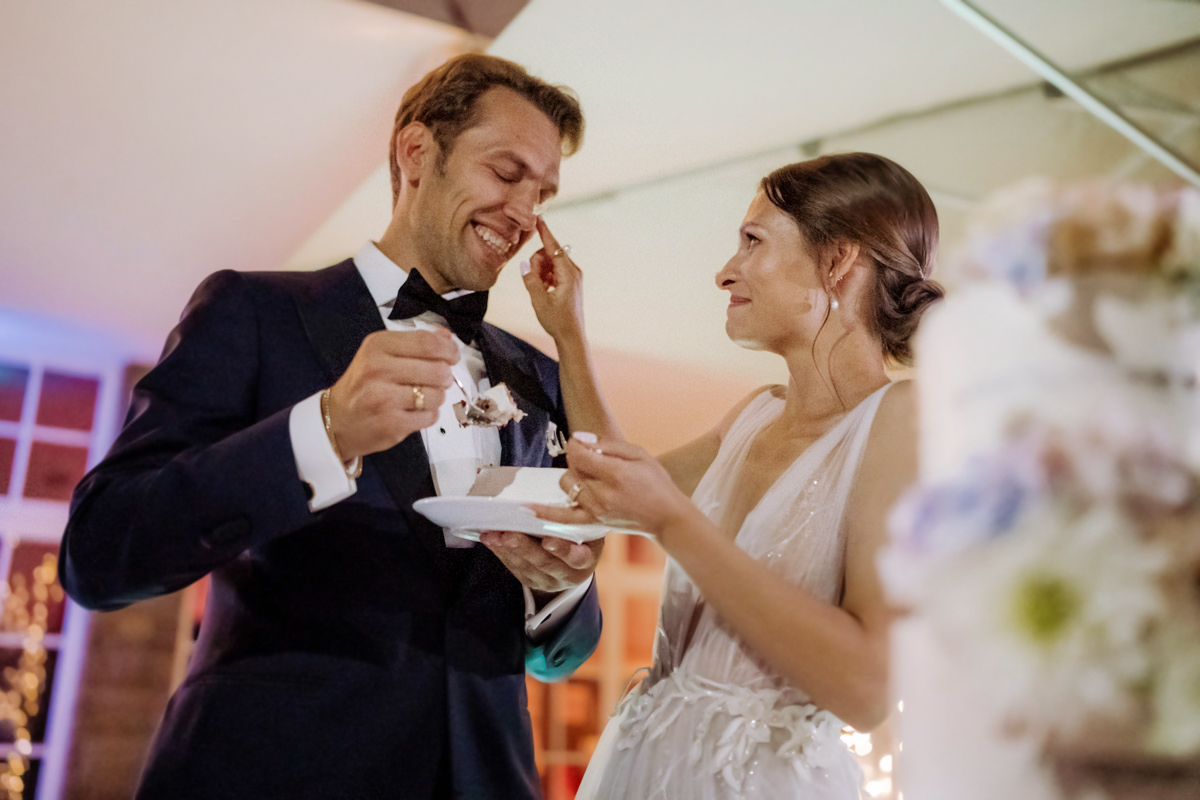 Braut streicht Bräutigam Hochzeitstorte an die Nase