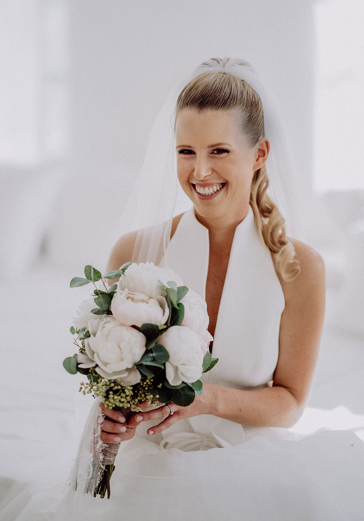 Braut mit Pfingstrosen Brautstrauß strahlt glücklich