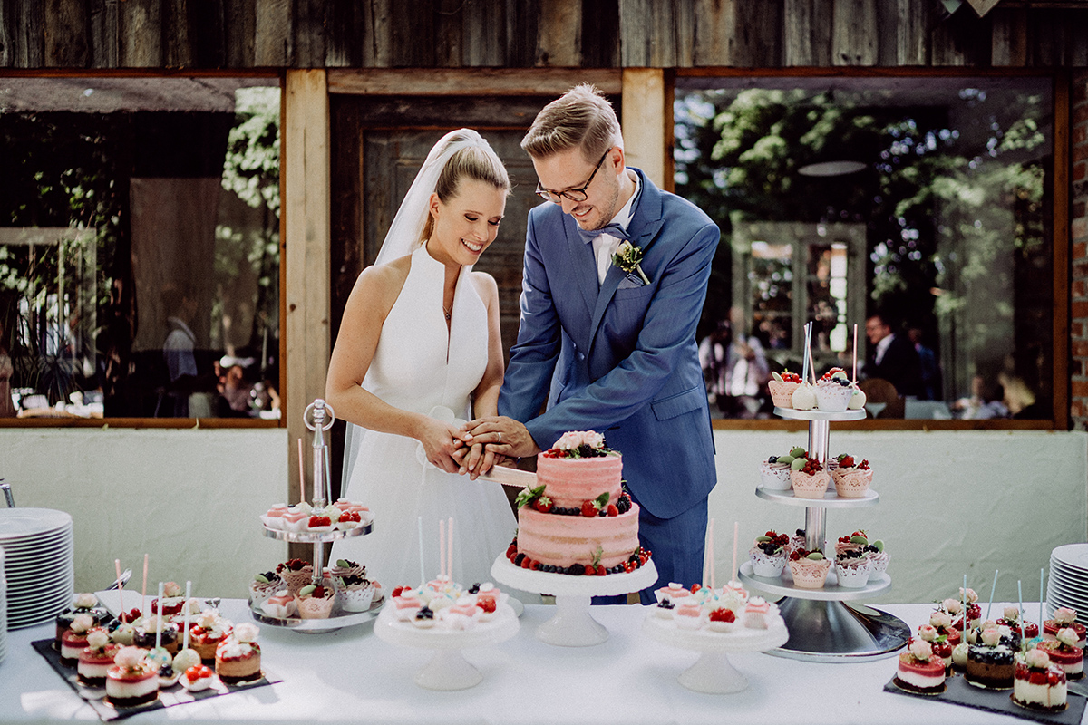 Hochzeitsreportage: Paar schneidet Hochzeitstorte vor Bleiche im Spreewald an
