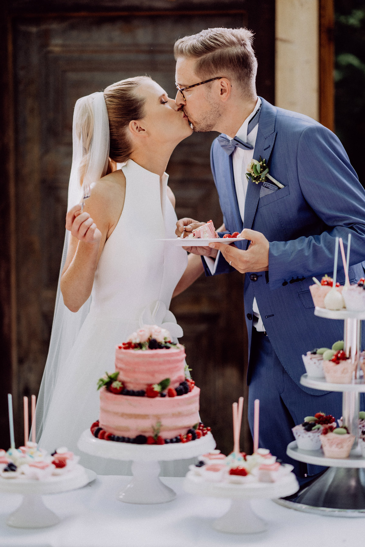 Hochzeitsmoment: Brautpaar küsst sich beim Anschnitt rosa Hochzeitstorte - Naked Cake ohne Fondant