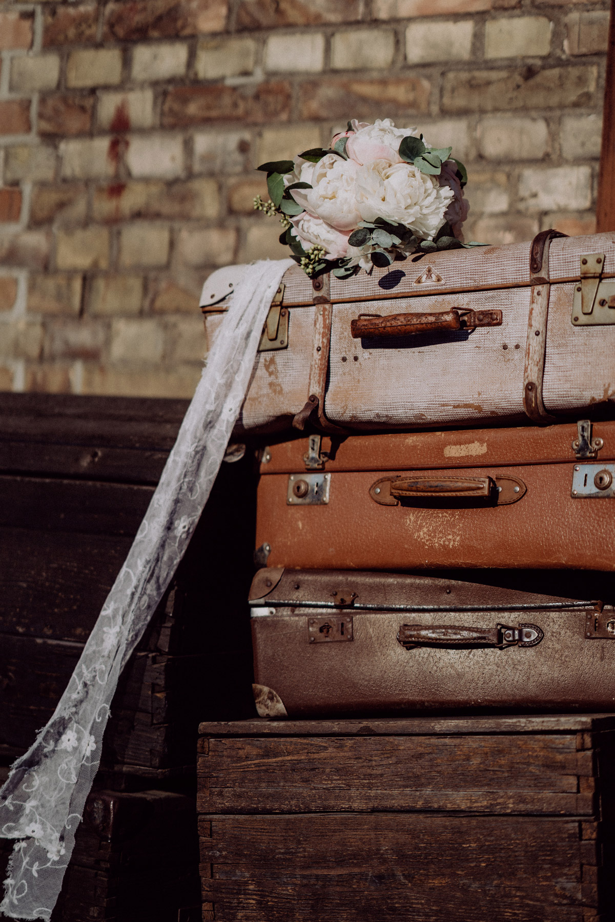 Brautstrauß mit Pfingstrosen liegt auf Koffer