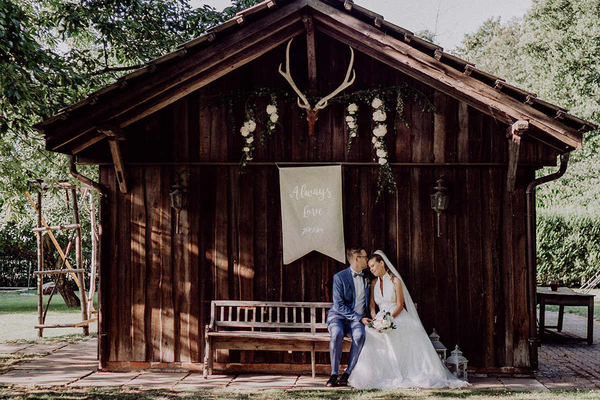 Bleiche Hochzeit: Paar sitzt vor typischem Spreewald Haus auf Bank