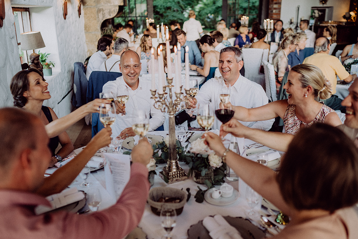 Gäste sitzen an runden Tischen und stoßen an