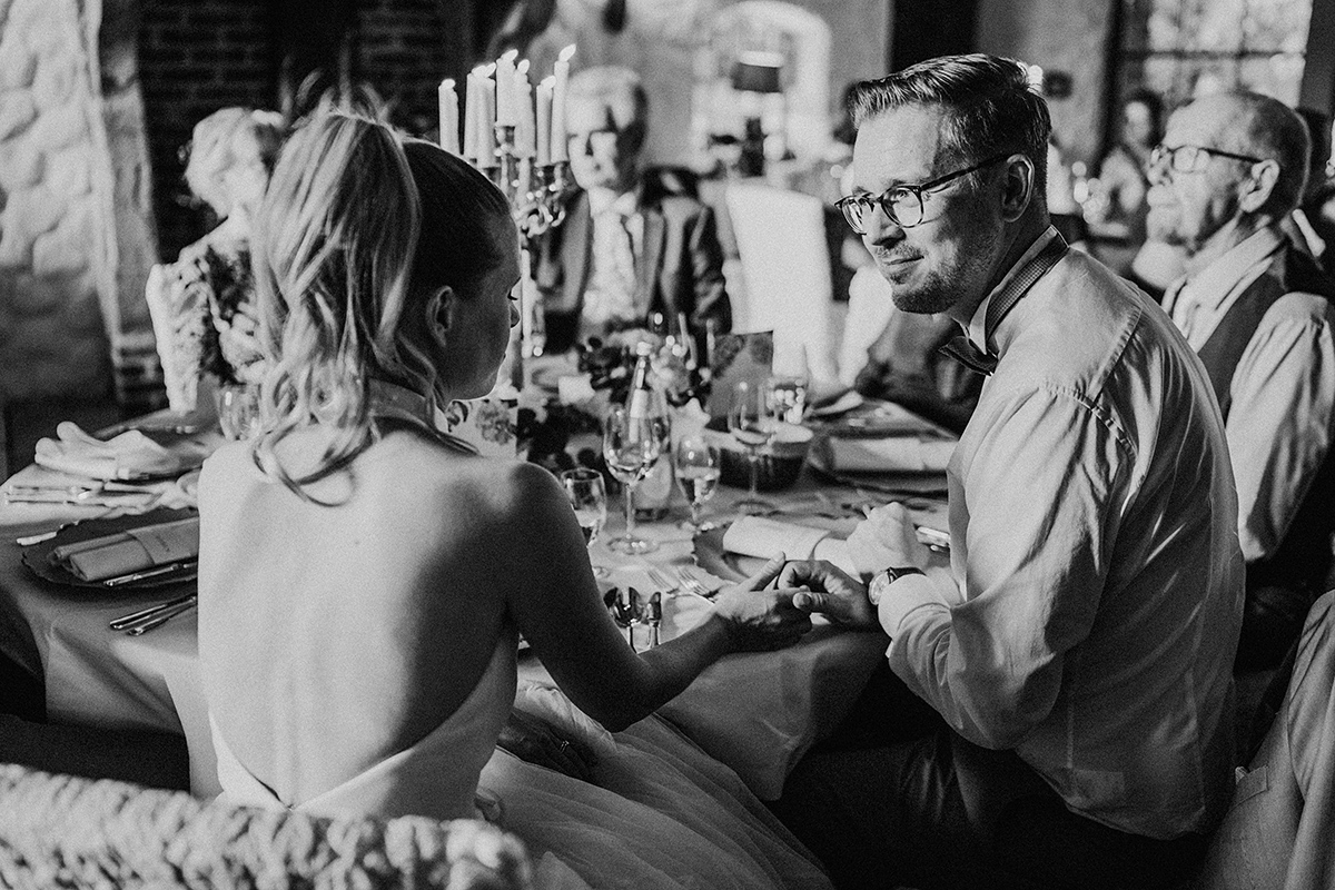 Hochzeitspaar hält sich an der Hand in Schwarz-Weiß