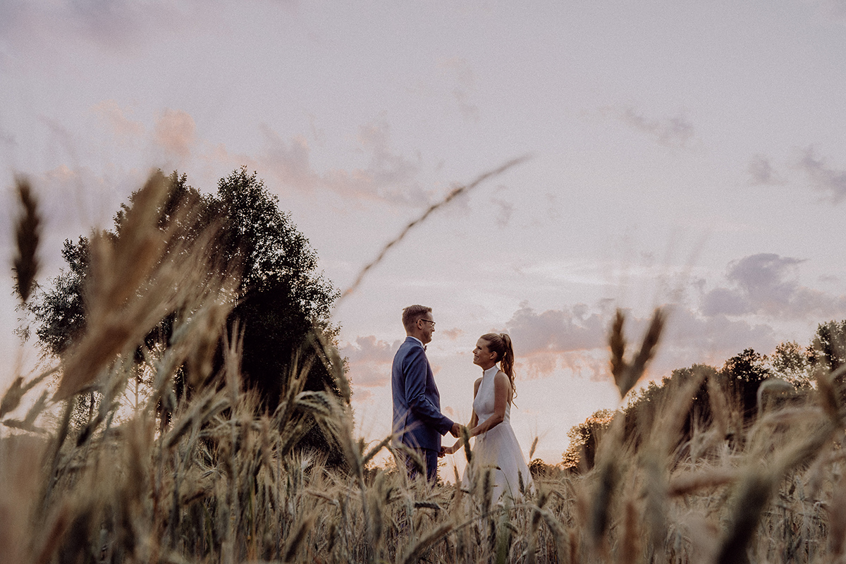 Brandenburg Hochzeitsfotografie: Paar steht auf Feld im Sonnenuntergang