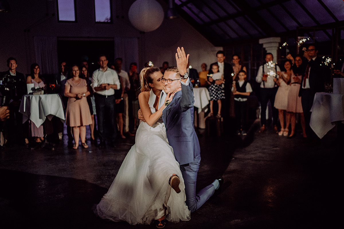 Hochzeitstanz Bräutigam kniet nieder und Braut küsst ihn
