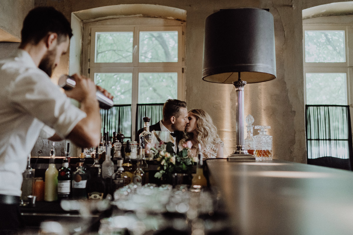 Kuss an der Bar: Stimmungsvolle Elopement Hochzeitsfeier im The Grand Berlin mit Barkeeper im Hintergrund
