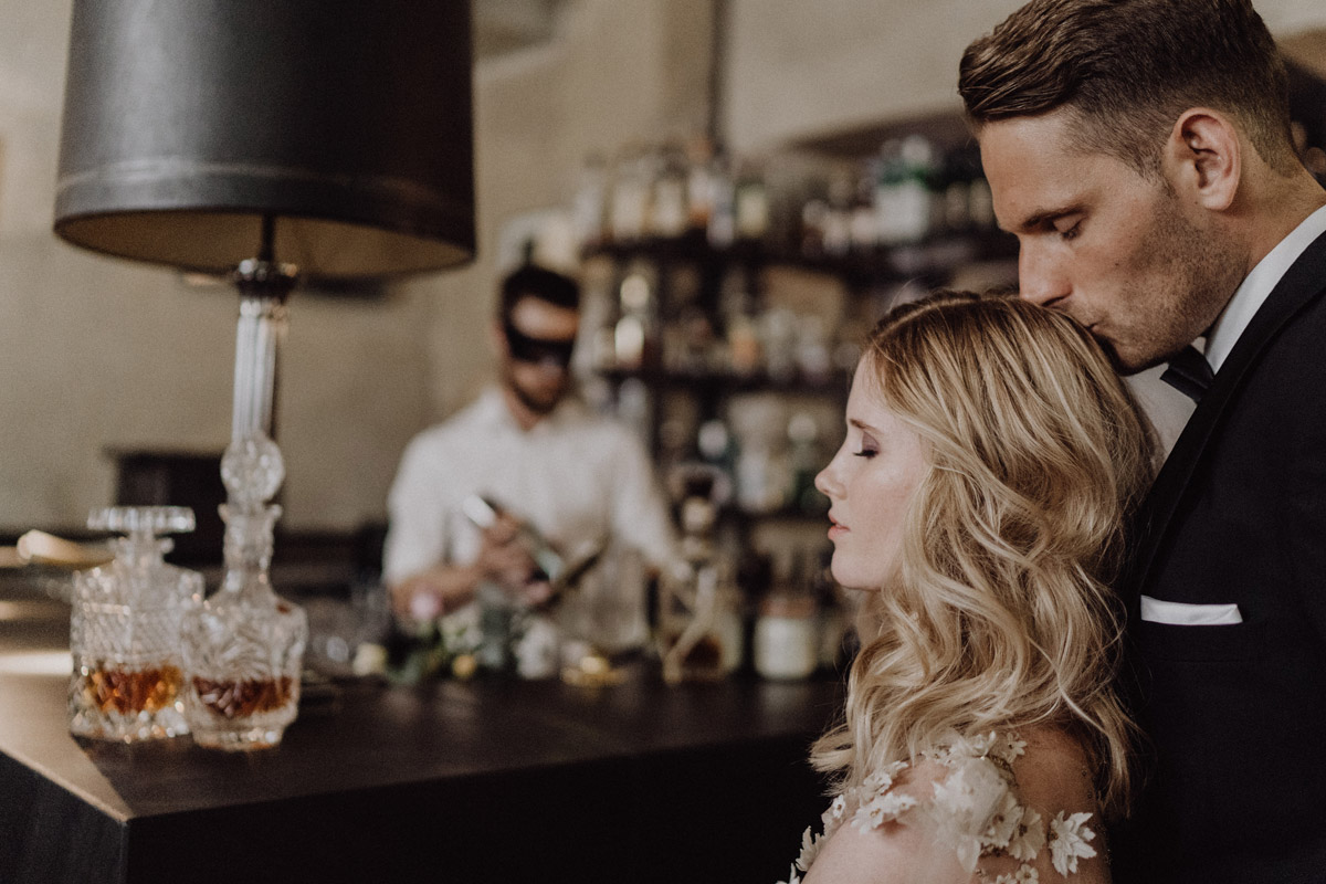 Zärtlicher Moment an der Theke: Bräutigam küsst Braut auf die Stirn in der Bar des The Grand