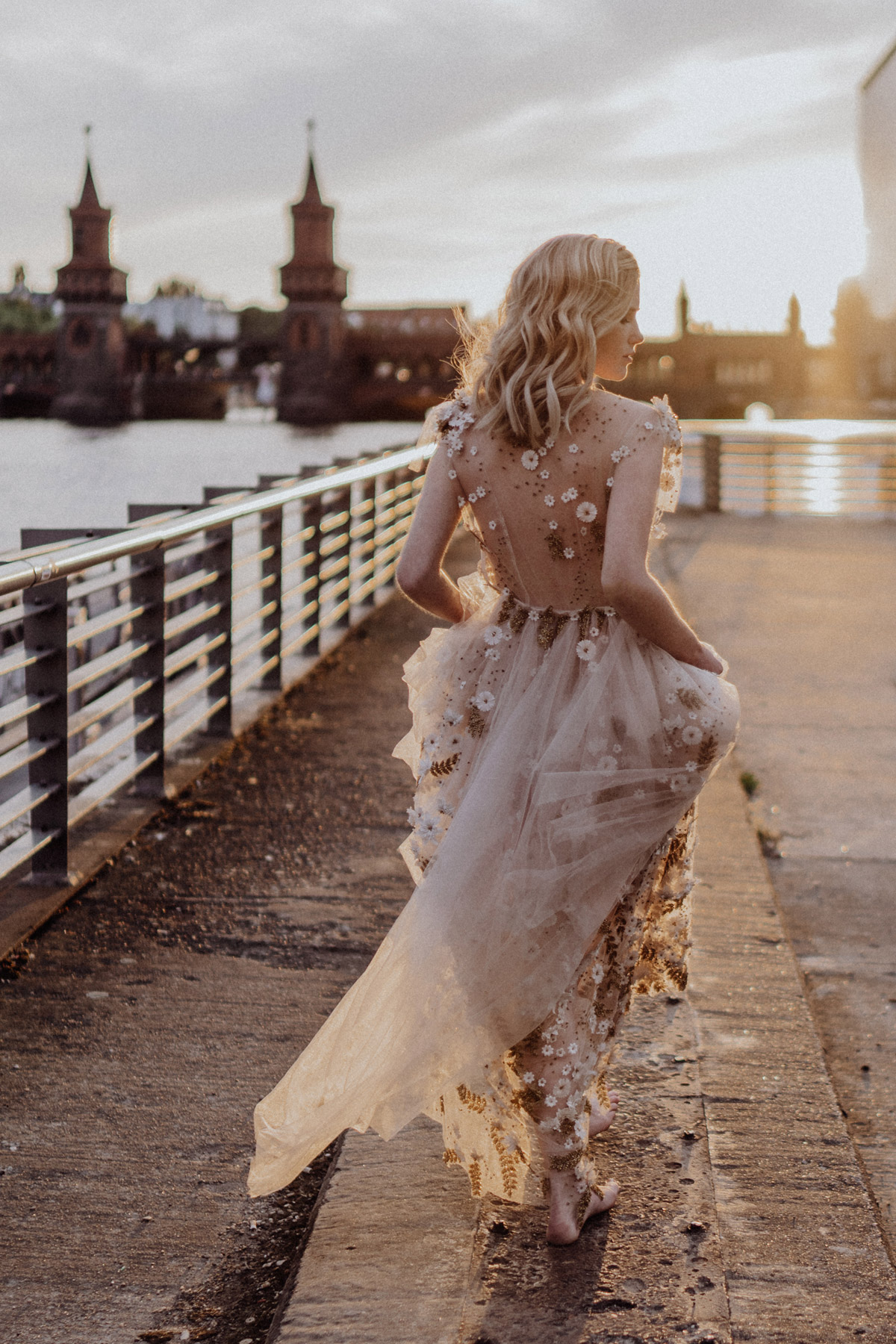 Braut im goldenen Abendlicht an der Spree: Künstlerische Aufnahme vom Hochzeitsfotograf Berlin mit Oberbaumbrücke im Hintergrund