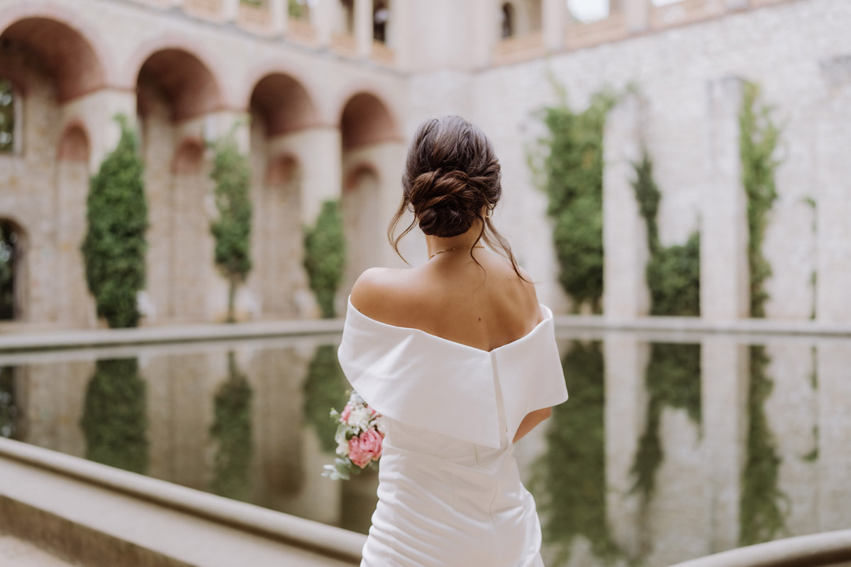 Brautfrisur Dutt festgehalten vor Wasserbecken im Innenhof des Schlosses