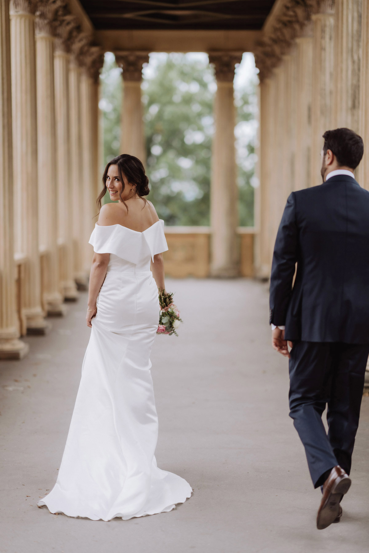 Braut und Bräutigam gehen und Braut schaut dabei über Schulter