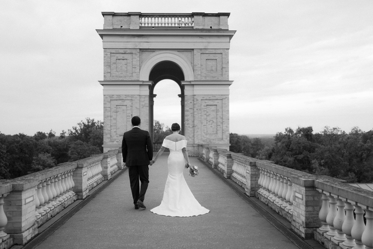 Hochzeitspaar von hinten geht auf Rundbogen des Ostturms im Belvedere zu