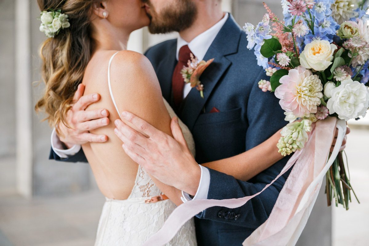 Hochzeitsfotograf Berlin Friedrichshain: Intimes Brautpaar-Portrait beim Kuss mit einem wunderschönen, wilden Brautstrauß in Pastellfarben