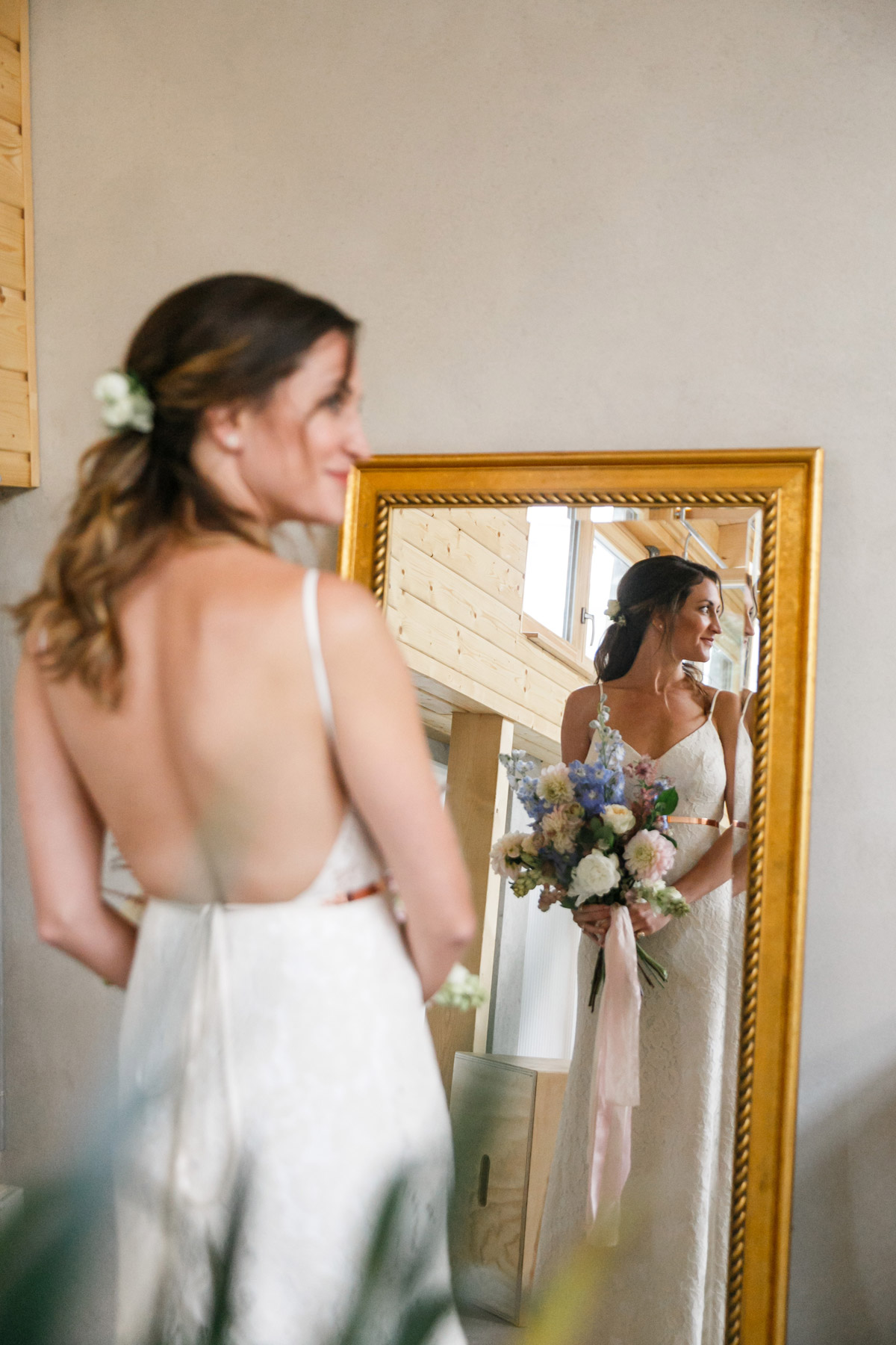 Braut von vorn im Spiegel beim Ankleiden