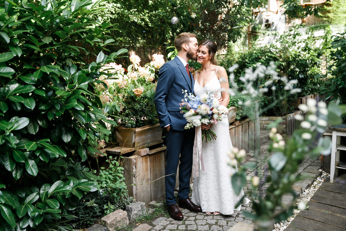 Hochzeitspaar steht im Garten des Old Smithy's Dizzle Berlin