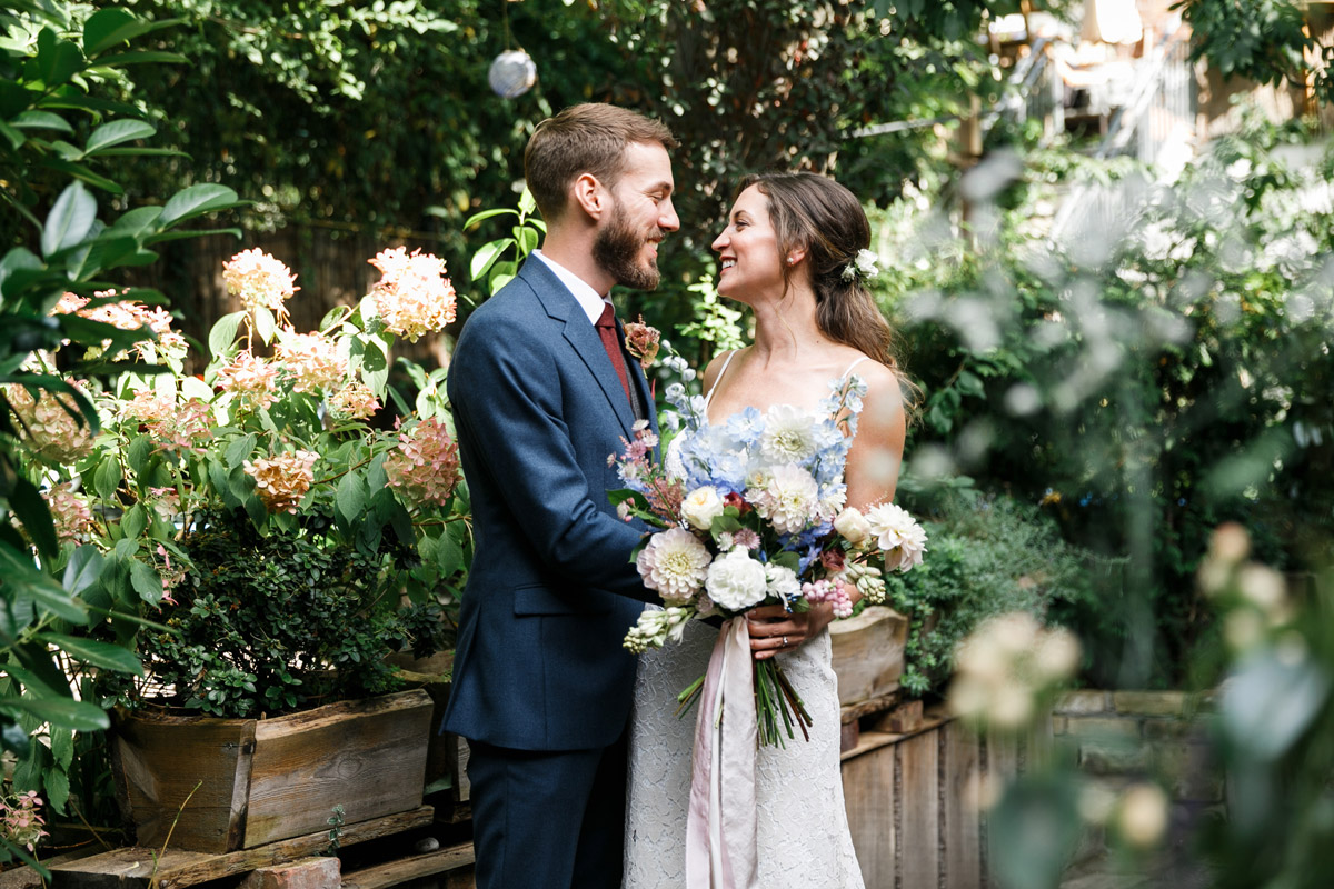 Emotionaler First Look im idyllischen Innenhof: Braut und Bräutigam strahlen sich im grünen Garten des Old Smithy's Dizzle glücklich an