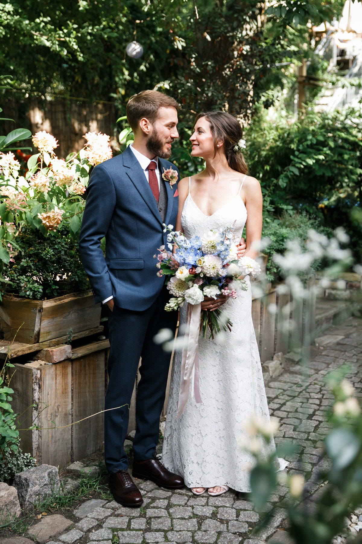 Heiraten in Berlin Friedrichshain: Entspanntes Hochzeitspaar beim Paarshooting auf dem Kopfsteinpflaster im Hinterhof der Alten Schmiede