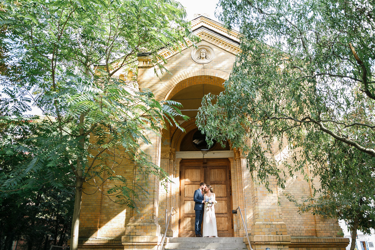 Hochzeitspaar steht vor schönem Backsteingebäude in Berlin Friedrichshain