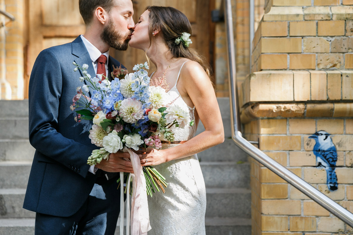 Hochzeitspaar küsst sich vor schönem Backsteinhintergrund