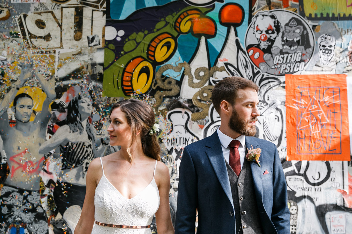 Cooles Hochzeitsfoto in Friedrichshain: Urbanes Brautpaar-Portrait vor einer farbenfrohen Street-Art- und Graffiti-Wand