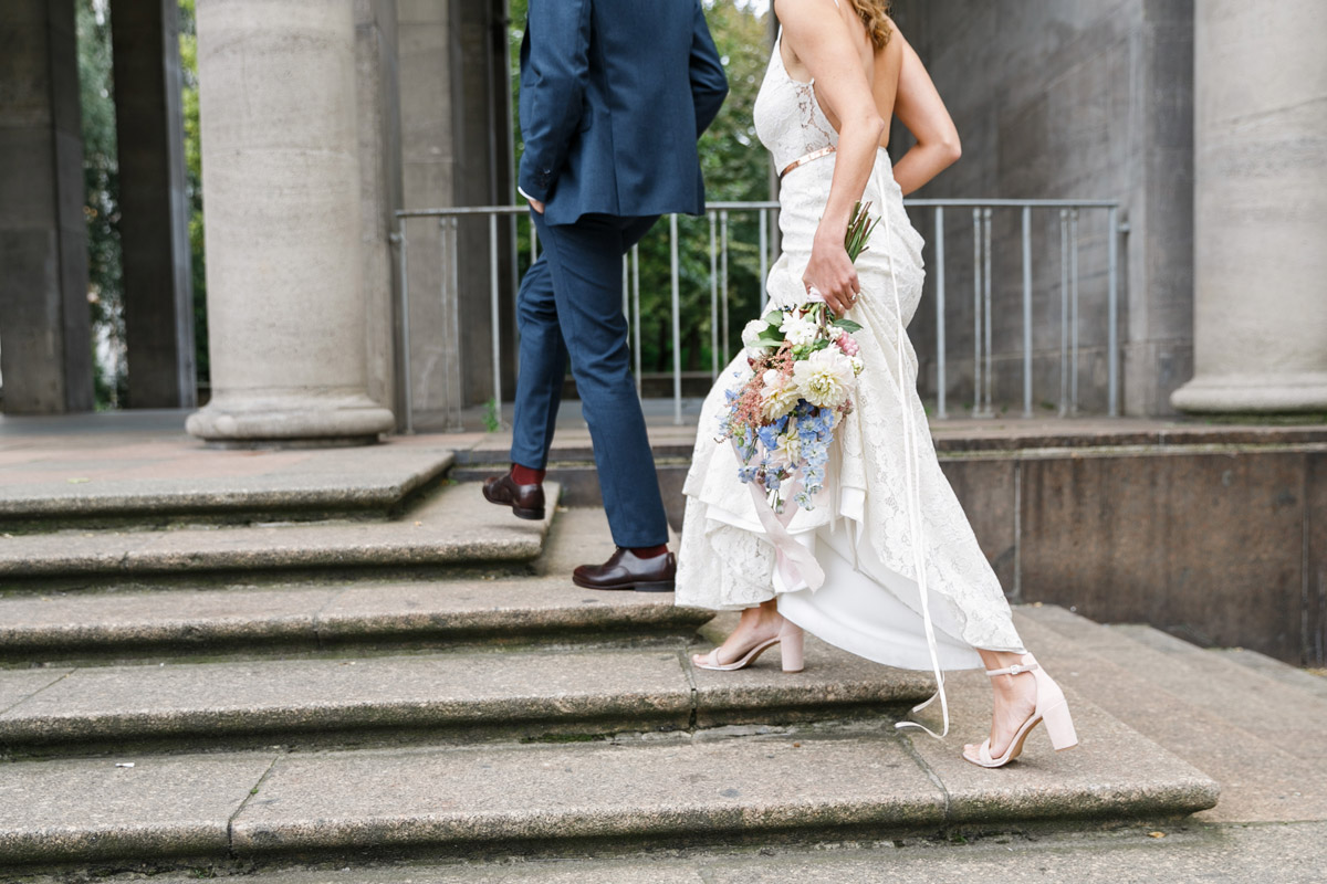 Detailaufnahme Schuhe und Beine des Hochzeitspaares beim Treppen steigen