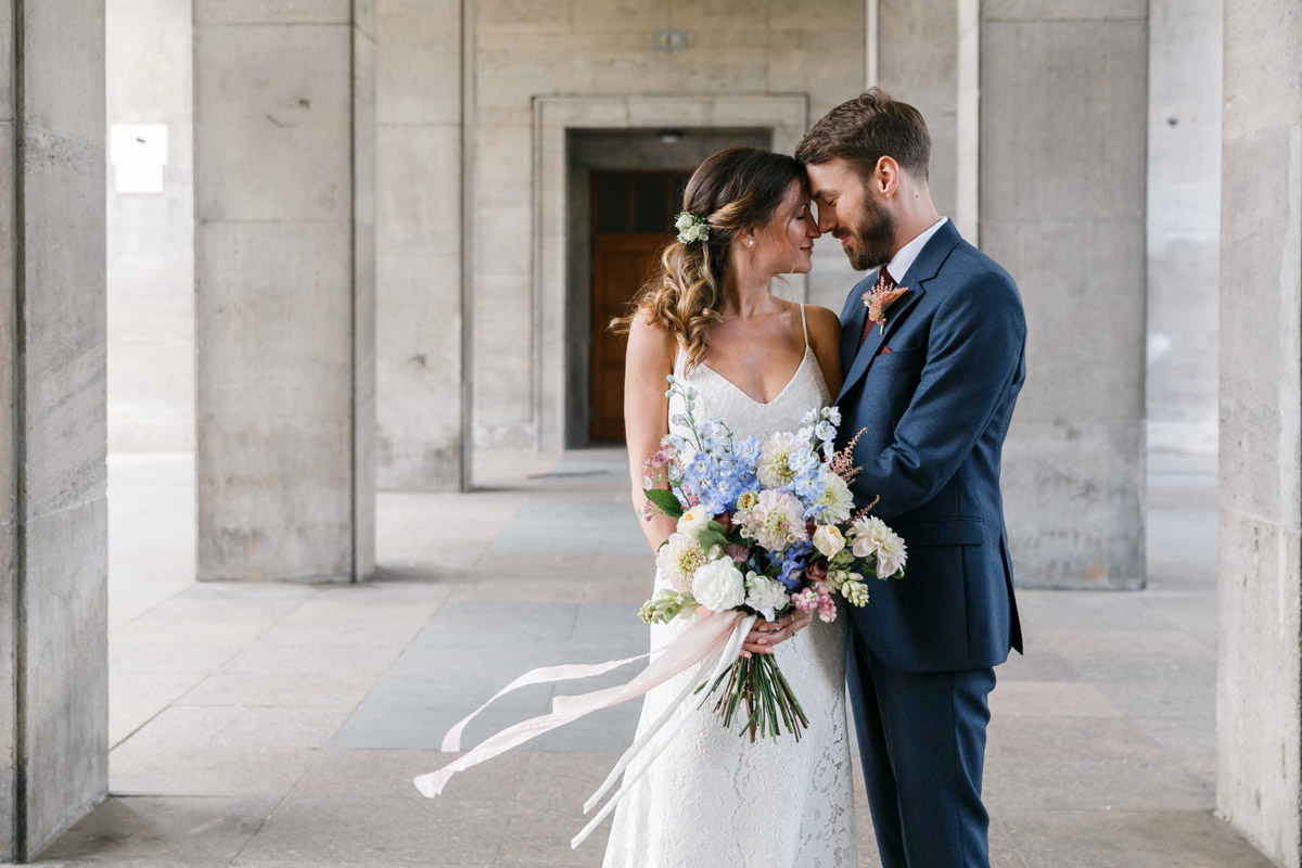 Hochzeitsfotograf Berlin Friedrichshain: Weitläufige Aufnahme des Brautpaares in inniger Umarmung zwischen den markanten Säulen der urbanen Location