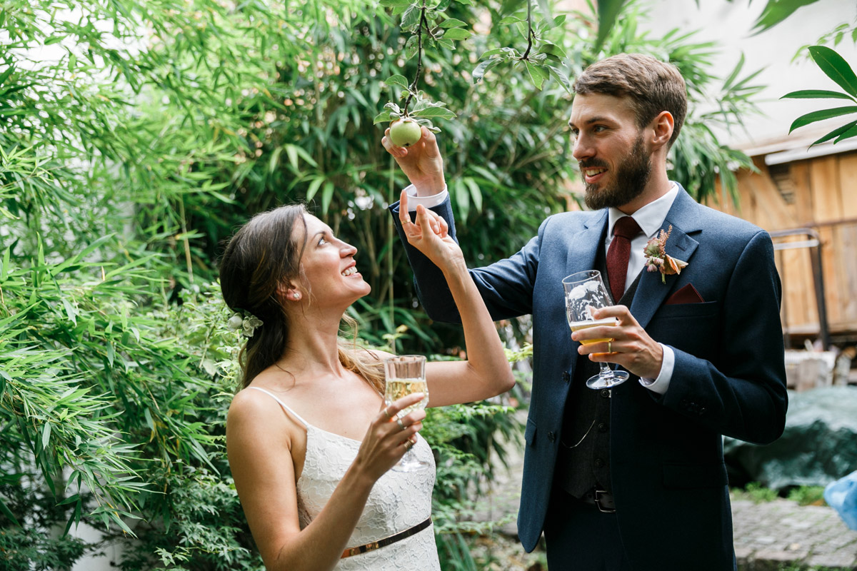 Brautpaar greift nach Apfel im Old Smithy Dizzle Garten im Berliner Hinterhof