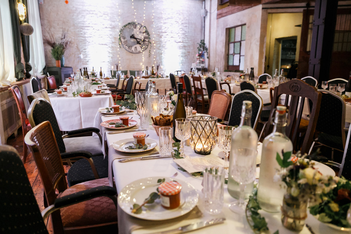 Heiraten im Old Smithy's Dizzle Berlin: Detailaufnahme der rustikal-eleganten Hochzeitstafel im historischen Saal der Alten Schmiede