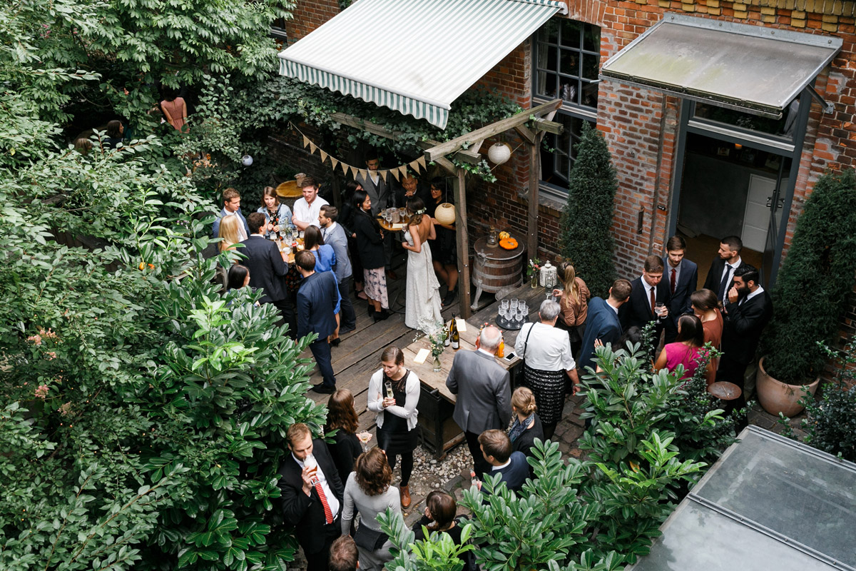 Hochzeitslocation Berlin Friedrichshain: Vogelperspektive auf die feiernden Hochzeitsgäste im grünen Innenhof der OSD