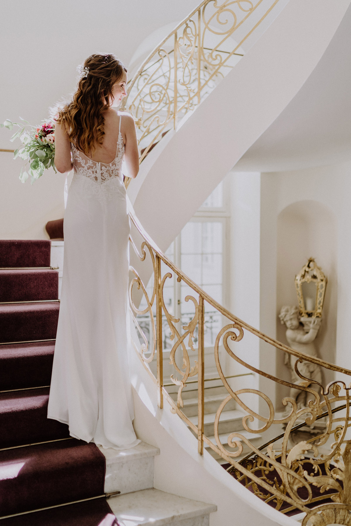 Braut schreitet die prunkvolle Treppe im Ermelerhaus hinab – Elegante Hochzeitsreportage in Berlin Mitte