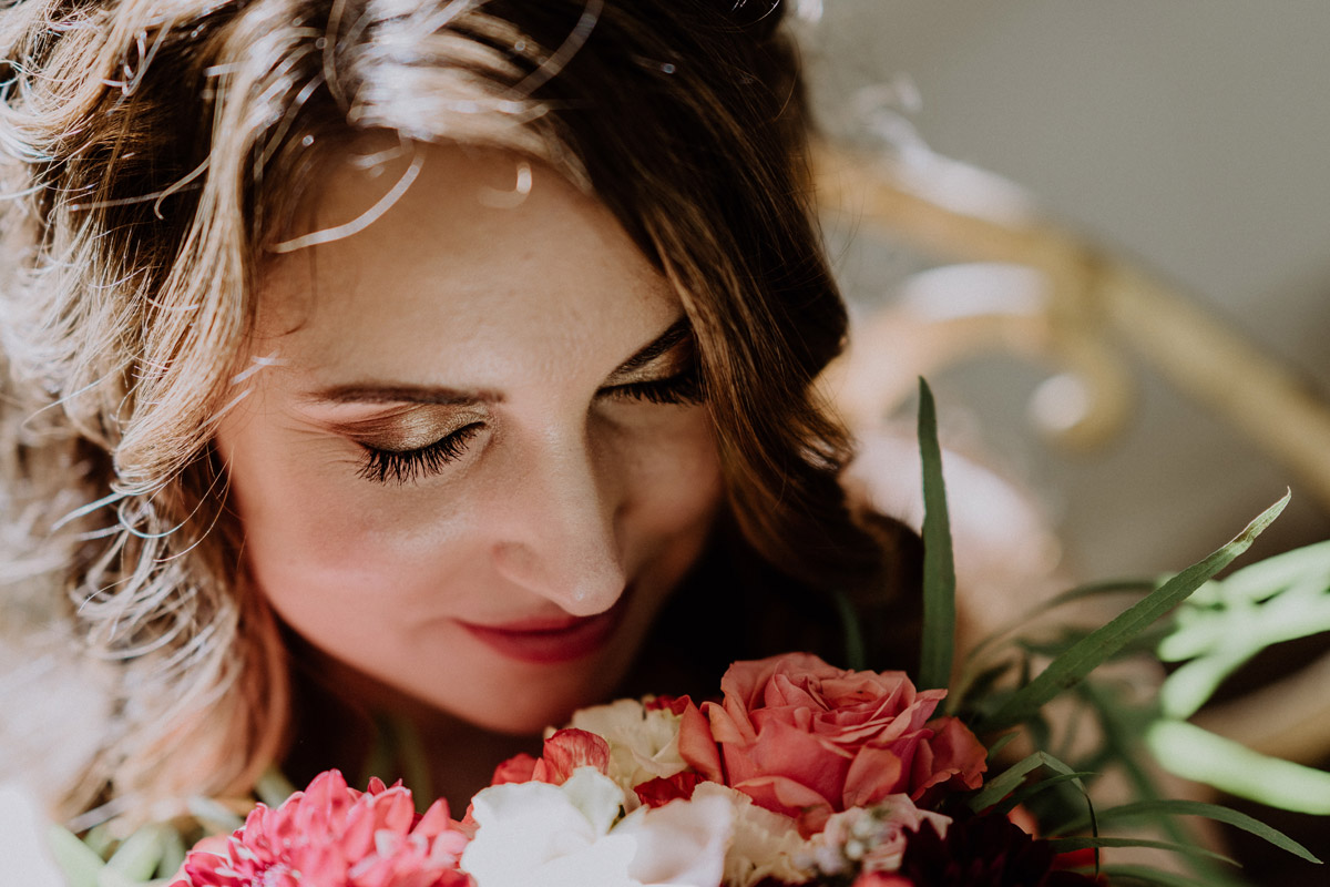Intimes Brautportrait im Ermelerhaus: Glückliche Braut schließt die Augen und genießt den Duft ihres detailreichen Brautstraußes