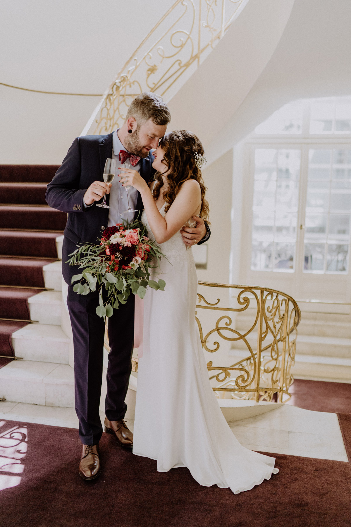 Sektempfang nach der Trauung: Brautpaar stößt mit Champagner auf der goldenen Treppe im Ermelerhaus an