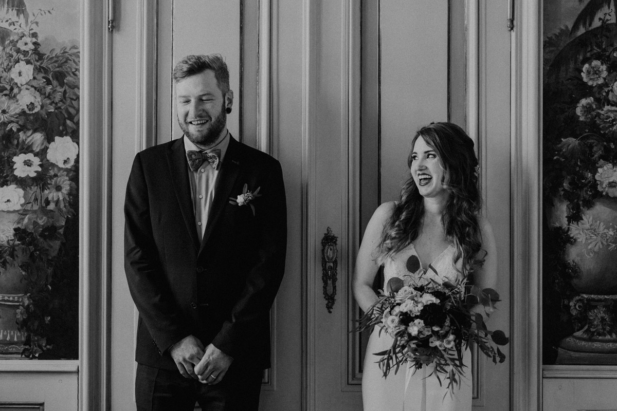 Natürliche Hochzeitsfotografie: Braut und Bräutigam lachen herzlich vor den historischen Türen im Standesamt Ermelerhaus