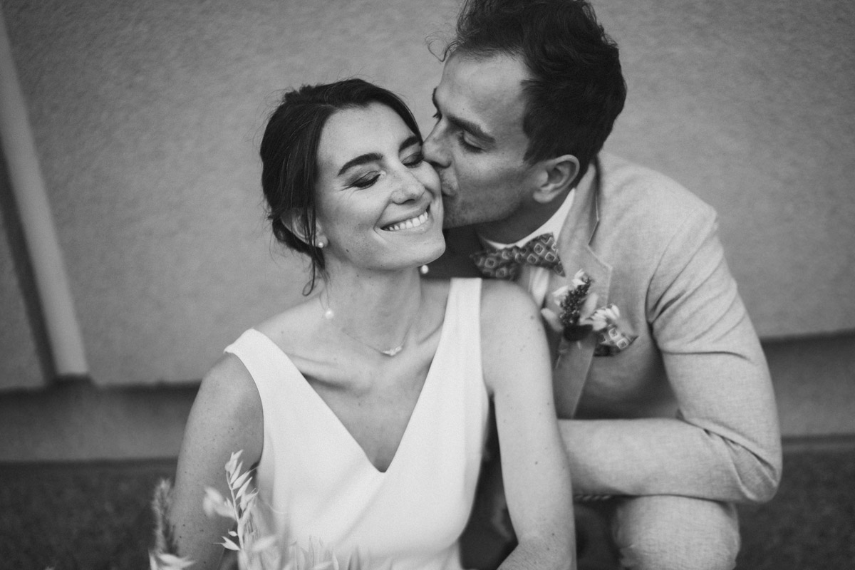 Braut genießt den Kuss des Bräutigams auf ihrer Wange - Schwarz-Weiß Aufnahme
