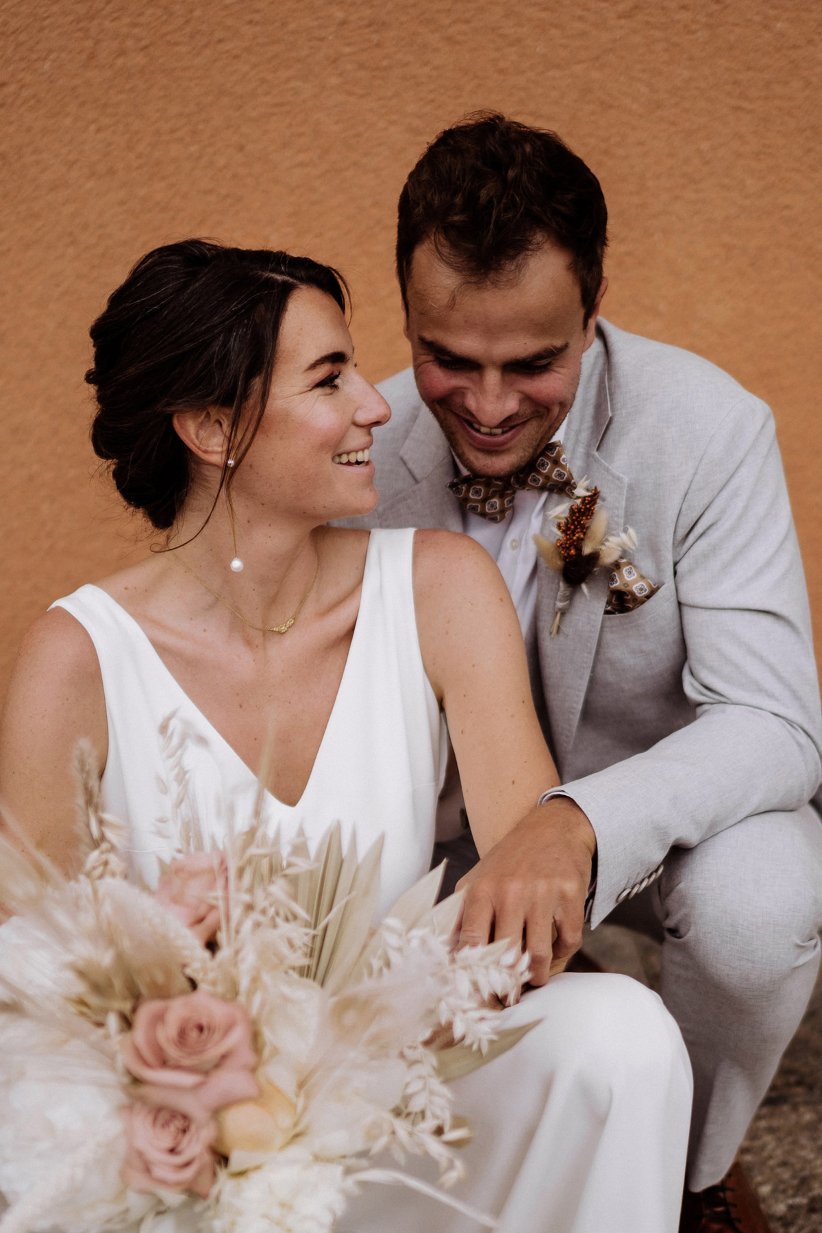 Cooles Brautpaarfoto mit hockendem Paar vor urbaner Kulisse