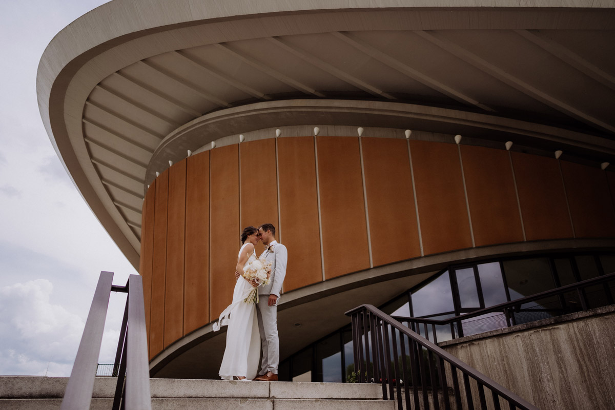Romantisches Paarshooting im Regierungsviertel: Braut und Bräutigam stehen innig auf der Treppe des HKW