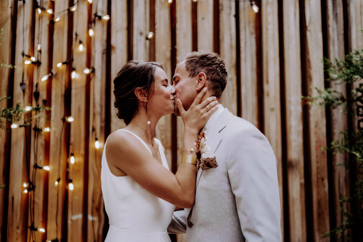 Brautpaar küsst sich vor romantischer Lichterwand