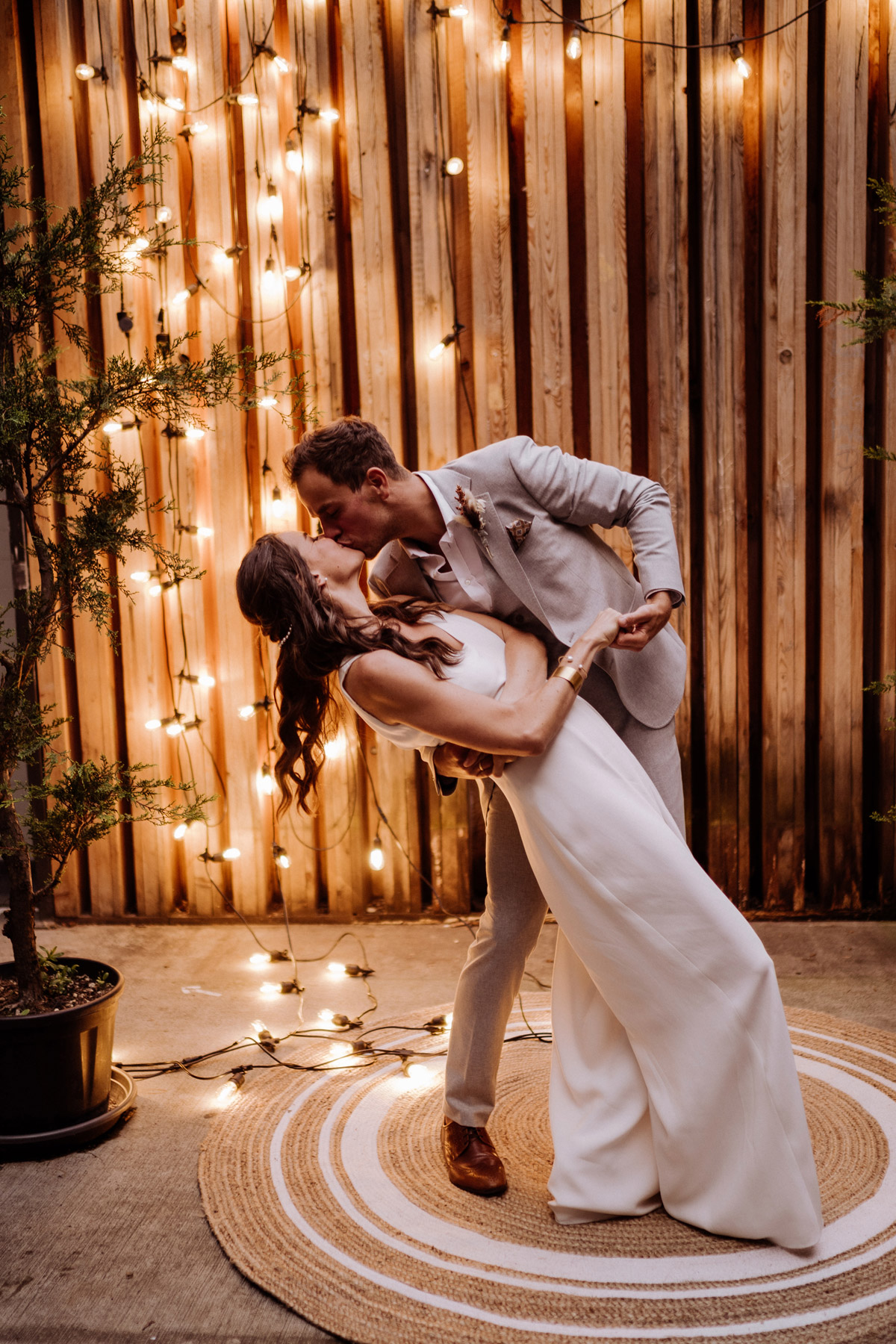 Leidenschaftlicher Kuss nach dem Ja-Wort: Romantischer Dip vor der Lichterwand im Innenhof