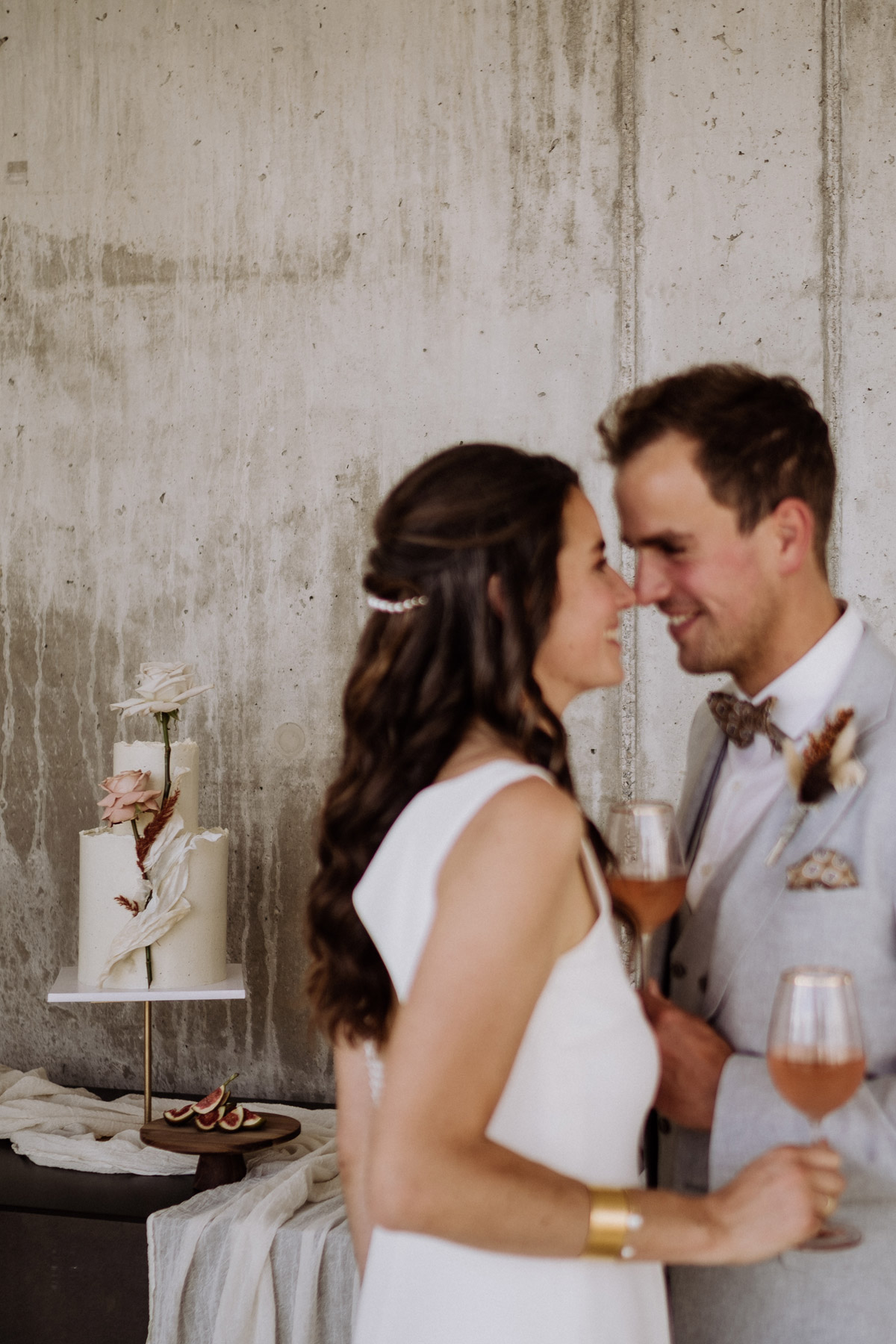 Kreative Hochzeitsreportage: Hochzeitstorte im Hintergrund ist scharf, das kuschelnde Paar vorne unscharf