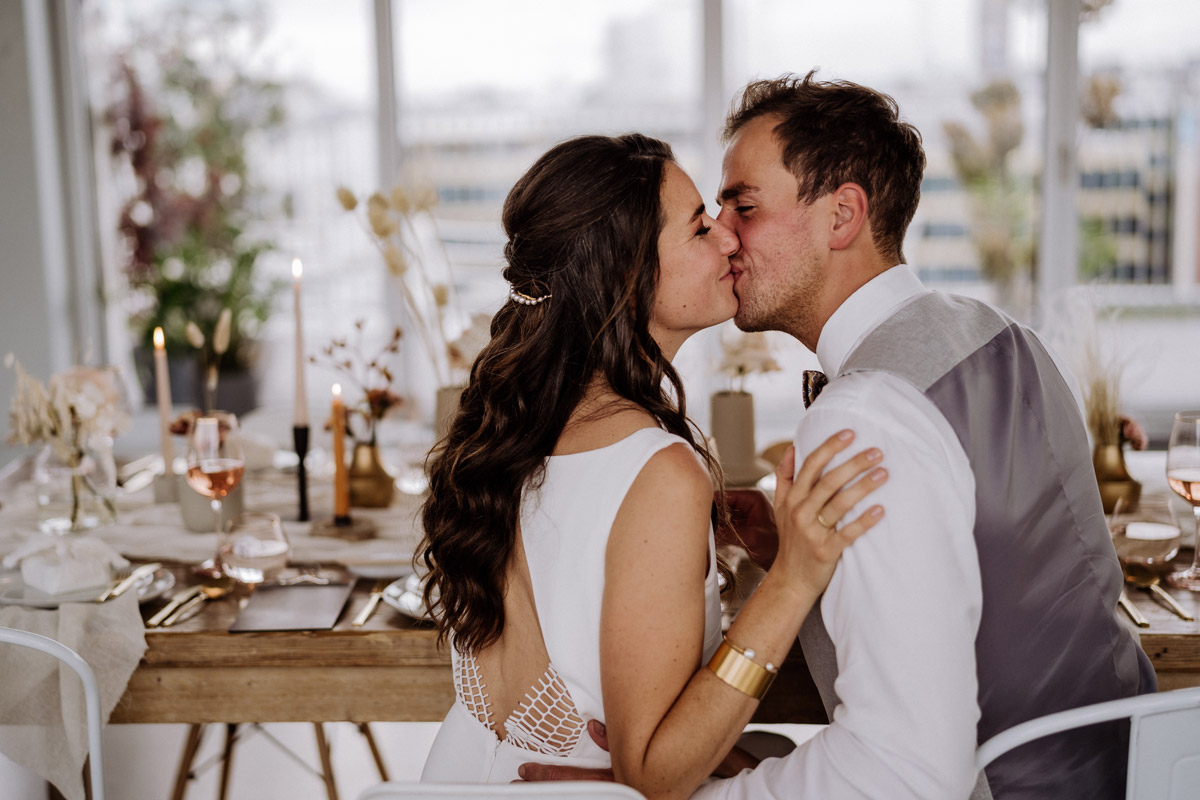 Brautpaar küsst sich am Hochzeitstisch
