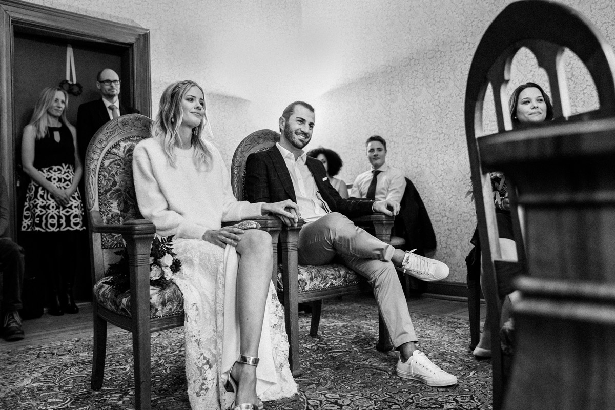 Trauzimmer Standesamt Charlottenburg-Wilmersdorf: Brautpaar lauscht glücklich der Standesbeamtin während der Trauung in der Villa Kogge (Schwarz-Weiß)